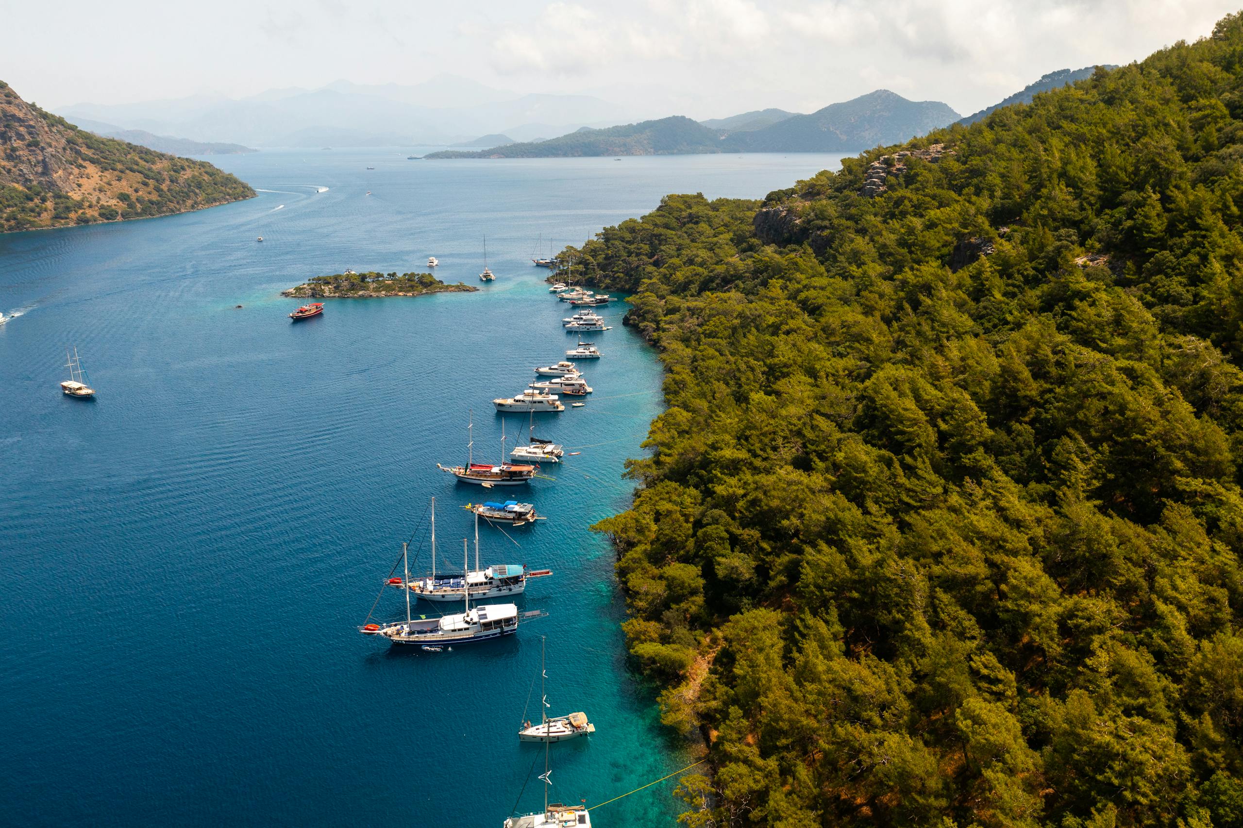 Stunning aerial view of Göcek Bay with boats and green forest coastline, perfect for travel enthusiasts.